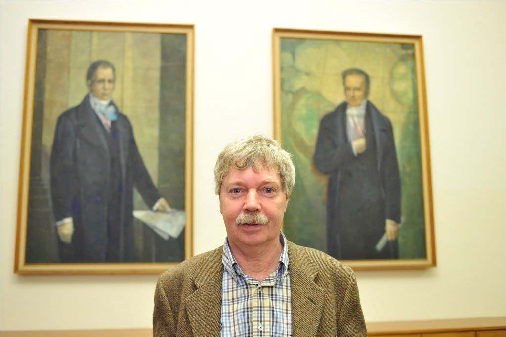 Rheinberger poses in front of the portraits of the Humboldt brothers