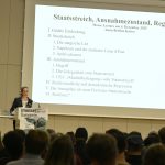 Kaiser lectures to the audience with a slide projected behind her