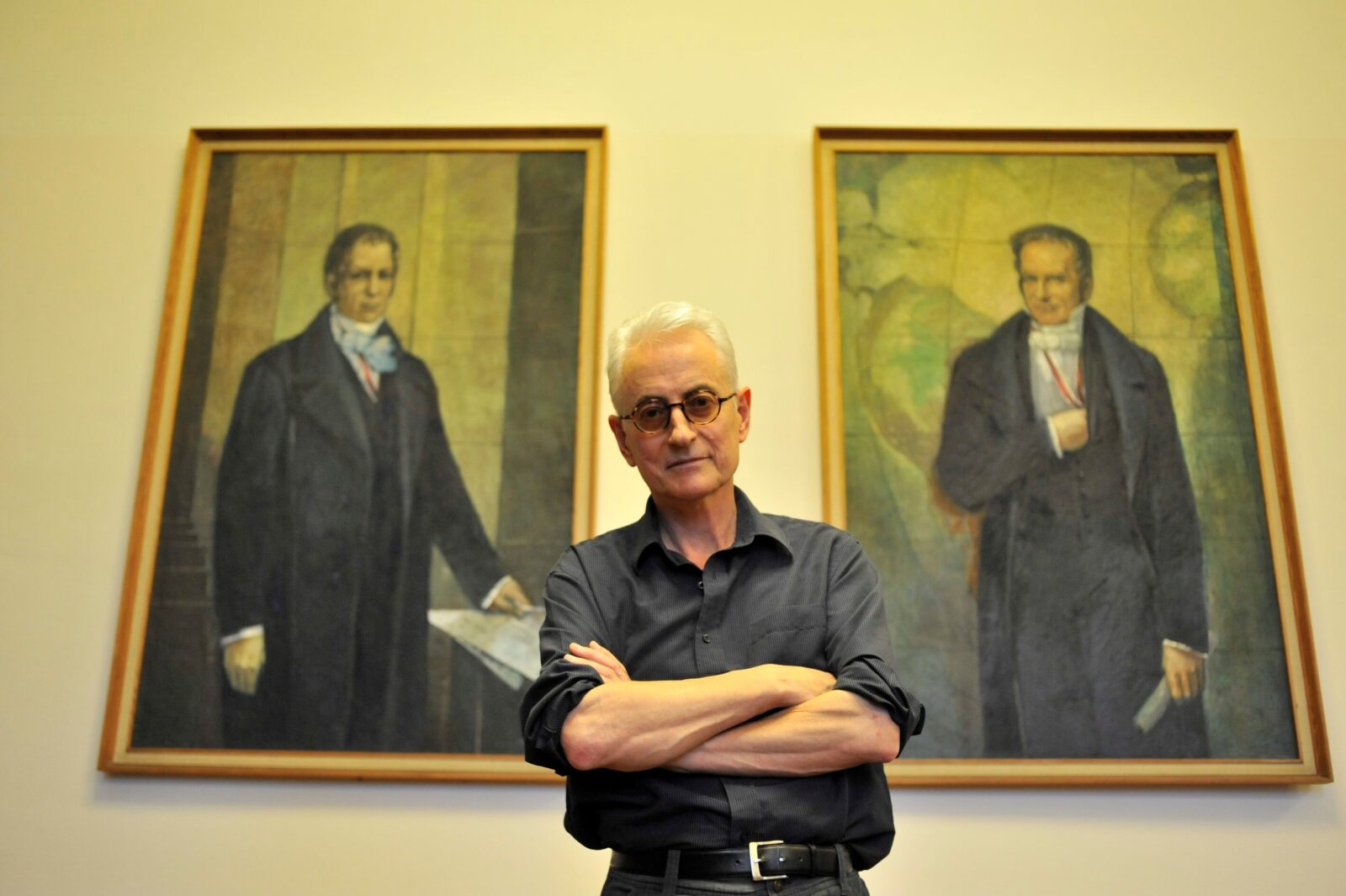 Jon Rose poses in front of the portraits of the Humboldt brothers