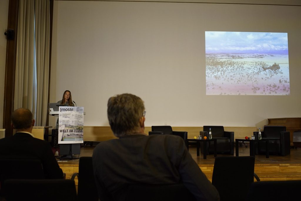 Hannah Cloke speaking with a slide of a river projected behind her