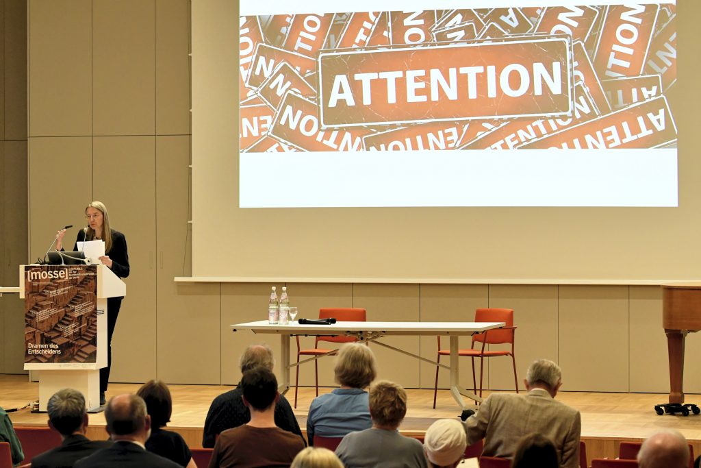 Auer speaks in front of slide