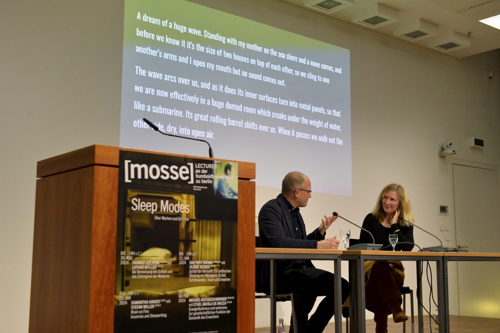 Samantha Harvey speaks with Stefan Willer, with powerpoint in the background