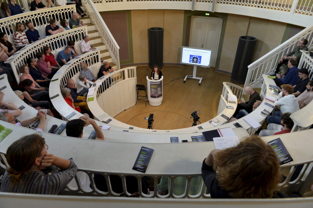 Anna-Verena Nosthoff speaks at the podium with the audience in the foreground