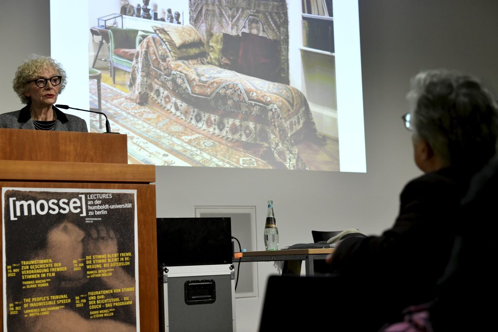 Sigrid Weigel delivering her lecture, with slide of a sofa in the background