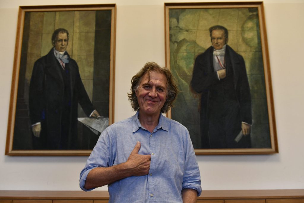 Norbert Scheuer poses in front of the portraits of Wilhelm and Alexander von Humboldt