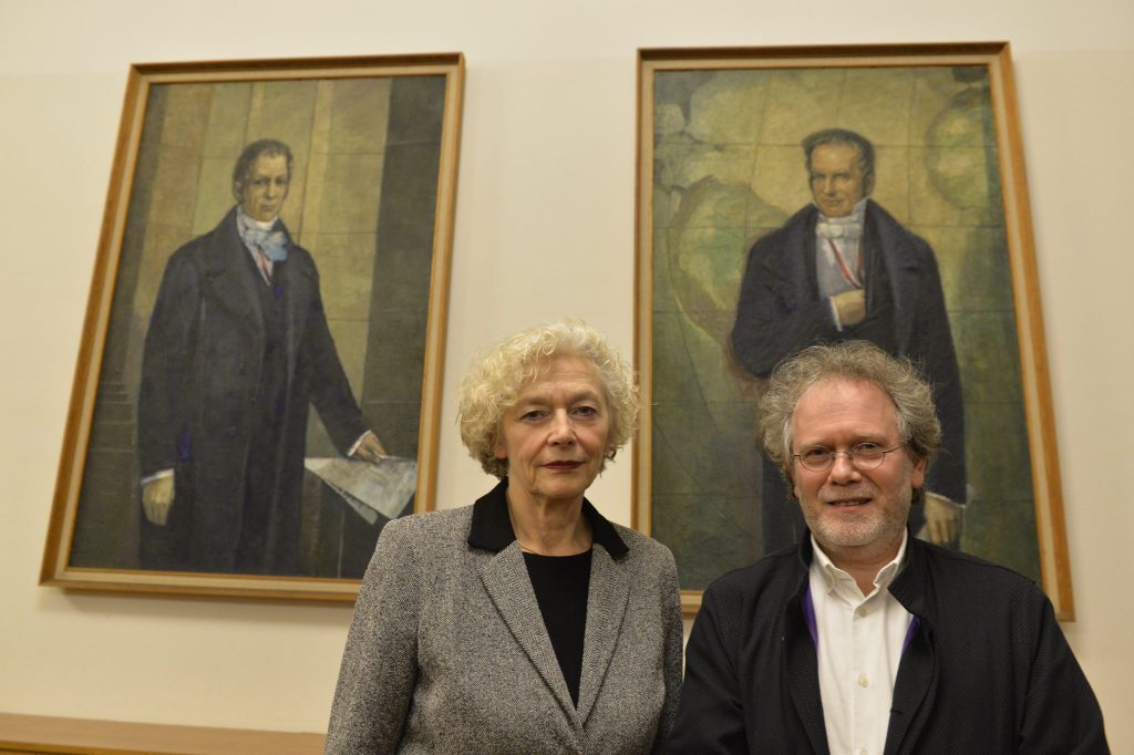 Huberman and Weigel pose in front of the portraits of the Humboldt brothers