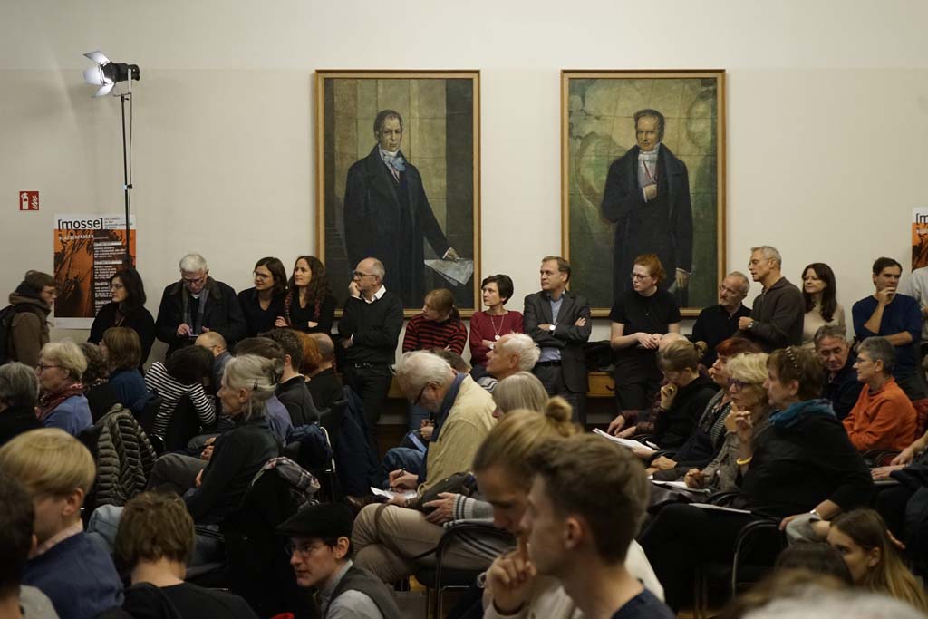 a full audience in front of the portraits of the Humboldt brothers