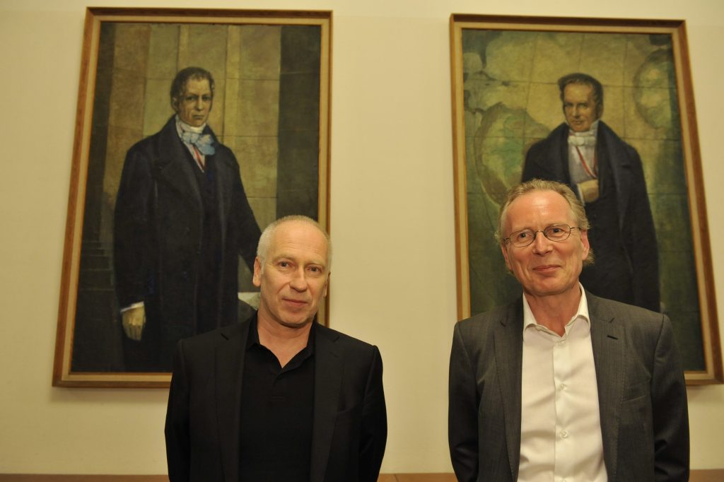 Menke and Vogl pose in front of the portraits of the Humboldt brothers
