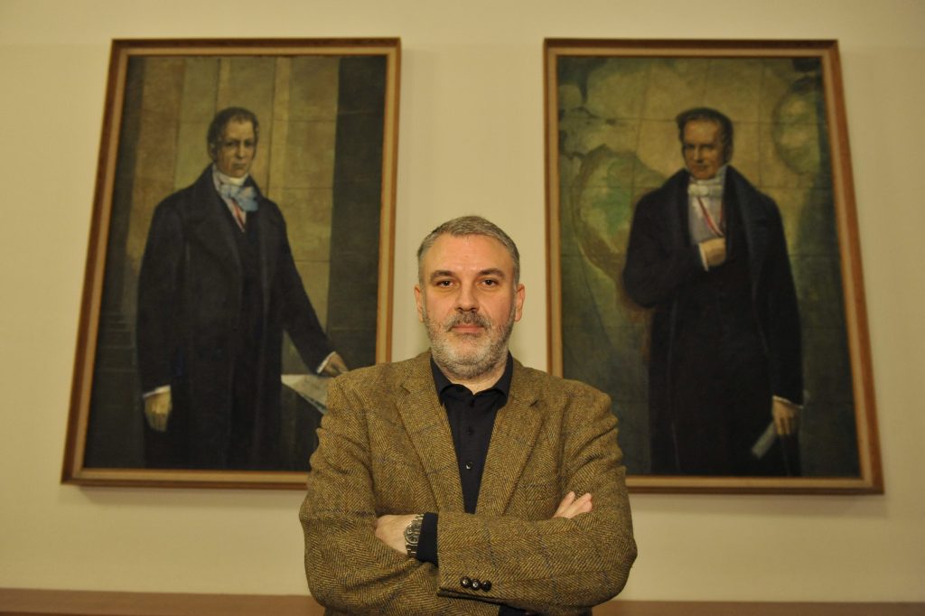 Stavrakakis poses in front of the portraits of the Humboldt brothers