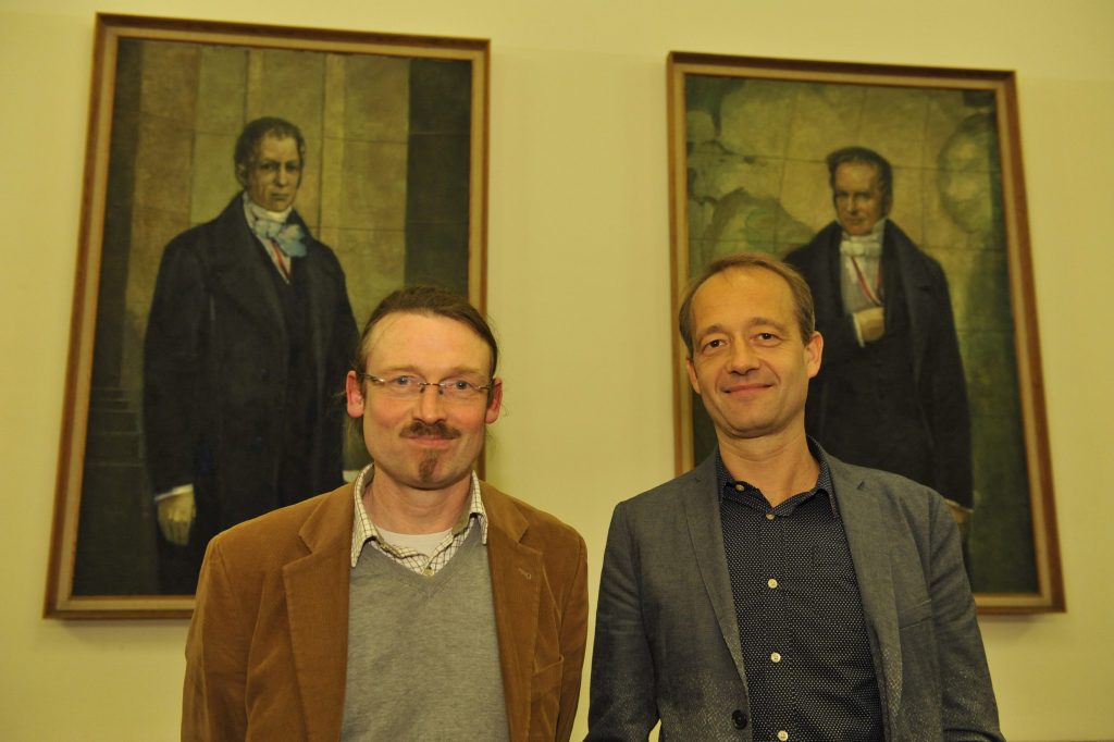 Stefan Weidner and Christoph Peters pose in front of the portraits of the Humboldt brothers