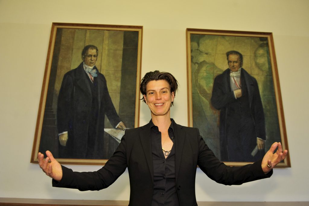 Emcke poses in front of the portraits of the Humboldt brothers