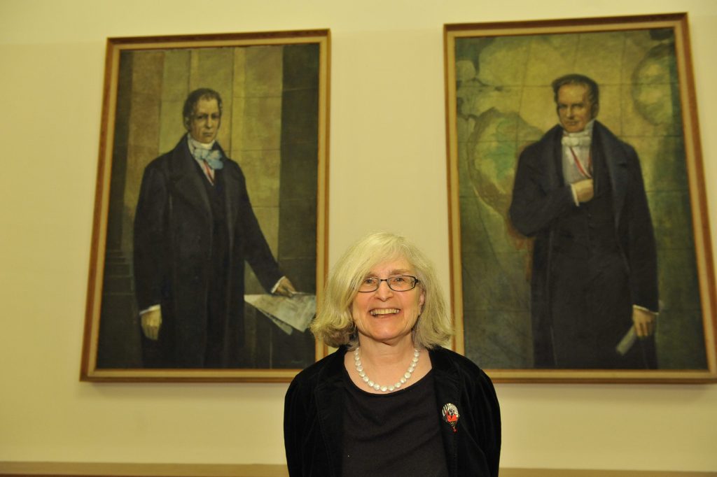 Diner poses in front of the portraits of the Humboldt brothers