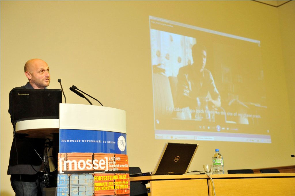 Levi at the podium, with a TV series playing in the background