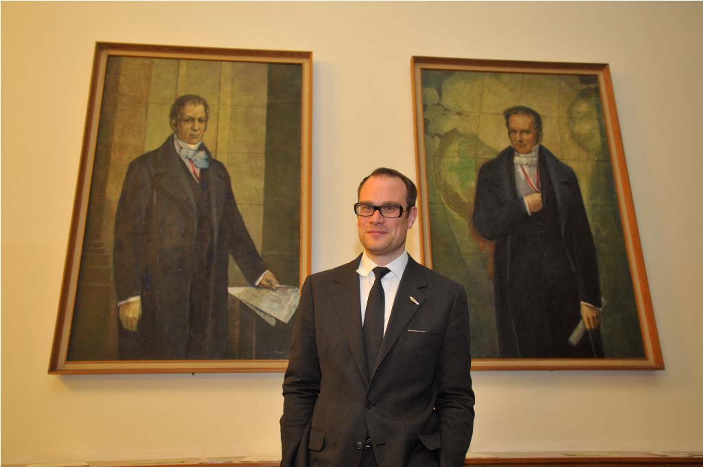 Jansen poses in front of portraits of the Humboldt brothers
